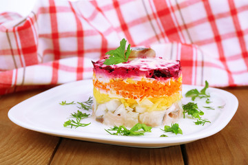 Russian herring salad on plate on wooden table background