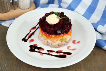 Russian herring salad on plate on wooden table background