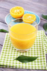 Glass of juice and ripe sweet tangerine on wooden table