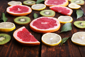 Ripe slices lemon, kiwi and grapefruit on wooden background
