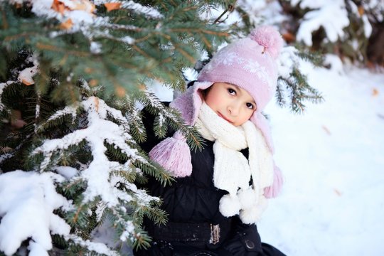 beautiful girl in purple winter hat under the Christmas tree
