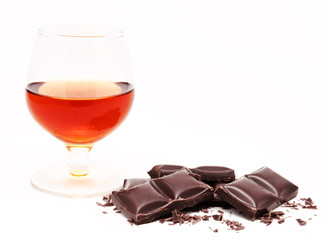 Glass with cognac and chocolate bars stack isolated on a white