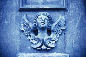 Sculpture of an angel on a wooden door in Italy - toned image