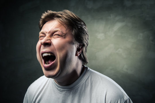 young angry man over dark grey background