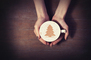 woman holding hot cup of coffee, with christmas tree shape