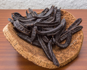 Carob pods on cortical stand. On the table.