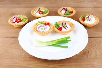 Tartlets with greens and vegetables with sauce on plate on