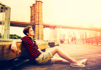 Young adult is sitting next to Brooklyn Bridge - 73725679