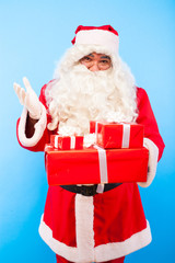 santa claus with gifts on hands on blue background