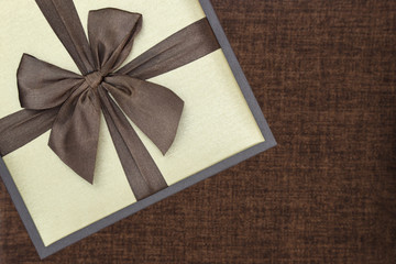 Gift box with ribbon on brown background