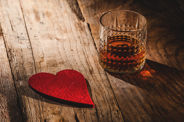 Heart and a glass of alcohol on a wooden table in the bar