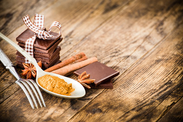 Chocolate, cinnamon and anise beside the wooden table.