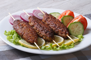 Grilled kebabs on wooden skewers and fresh vegetables