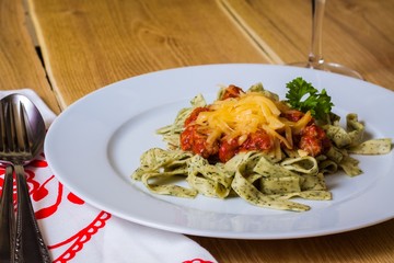 Green herb pasta with bolognese sauce on white plate