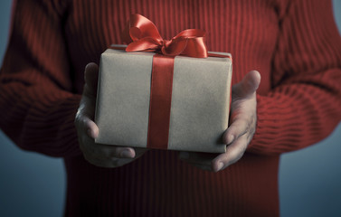 Male hands with red bow gift box.