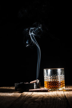 Glass Of Alcohol And Smoking Noble Cigar On A Black Background