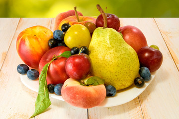 various ripe fruits on a plate on a blurred background