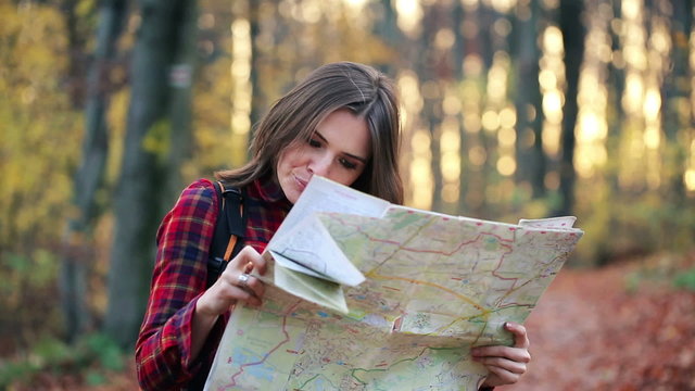 Young, pretty woman with map looking for direction in forest