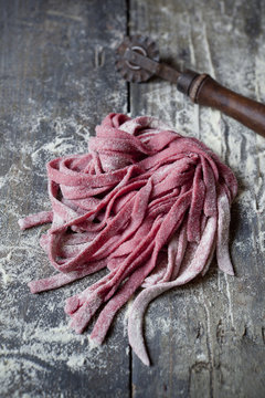 fresh tagliatelle with beetroot on rustic table with flour