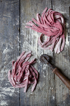 fresh tagliatelle with beetroot on rustic table with flour