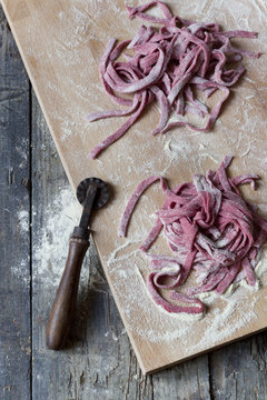 fresh homemade pasta tagliatelle with beetroot on chopping board