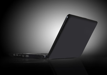 black laptop on black background with reflection
