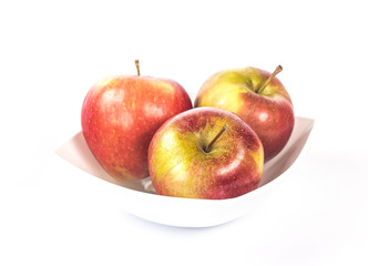 Three red apples in a white bowl