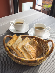 Toasts in basket with coffee on table.Breakfast set