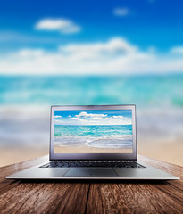 Laptop on wooden desk, view on the sea