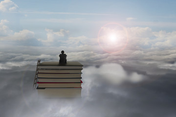 pondering businessman sitting on stack of books with sunlight cl
