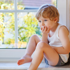 Little boy of three years looking out of the window on yellow au