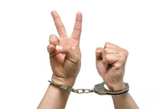 Man hands with handcuffs showing victory sign