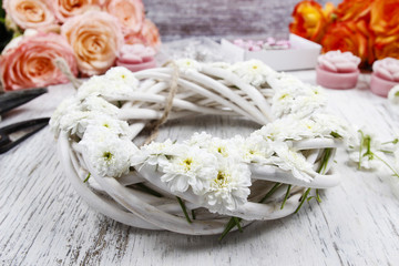 White wicker wreath decorated with tiny daisies