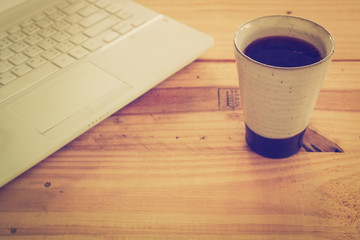 Cup of coffee and laptop on wooden table