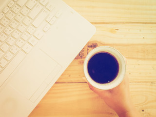 Cup of coffee and laptop on wooden table