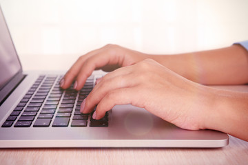 Female hands working on laptop on light background