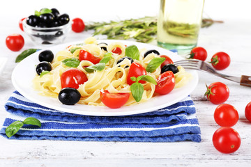 Spaghetti with tomatoes, olives and basil leaves