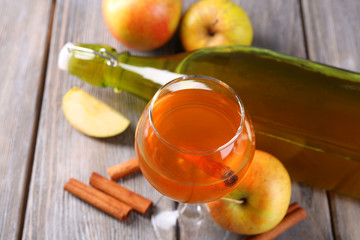 Apple cider in wine glass and bottle, with cinnamon sticks and