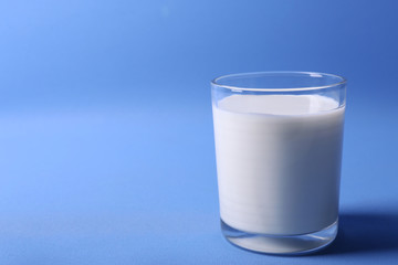 Milk in glass on blue background