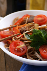 Chinese noodles with vegetables and roasted meat in bowl