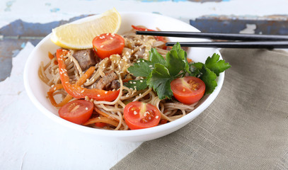 Chinese noodles with vegetables and roasted meat in bowl