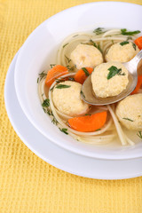 Soup with meatballs and noodles in bowl on wooden background