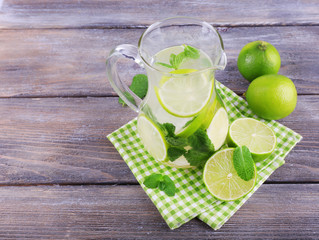 Lemonade in pitcher on wooden background
