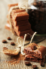Tasty porous chocolate with coffee beans, on wooden table