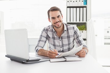 Casual businessman writing on newspaper