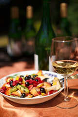 Still life with glass of white wine and sliced fruits