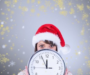 Composite image of festive brunette holding a clock