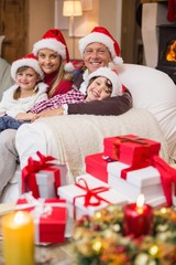 Festive family in santa hat hugging on couch
