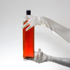 Gloves holding a bottle of red wine isolated on white background