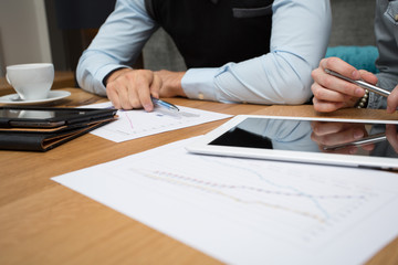 Holztisch mit Diagrammen / Kaffee und Tablet